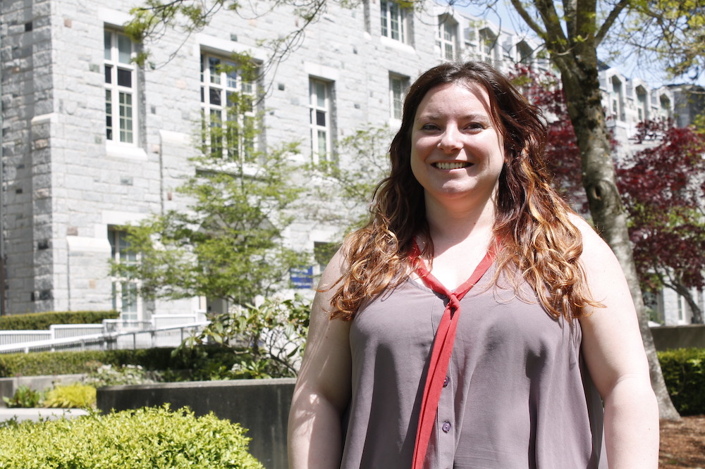 Emily Cadger smiles at the camera outside a stone building at UBC.