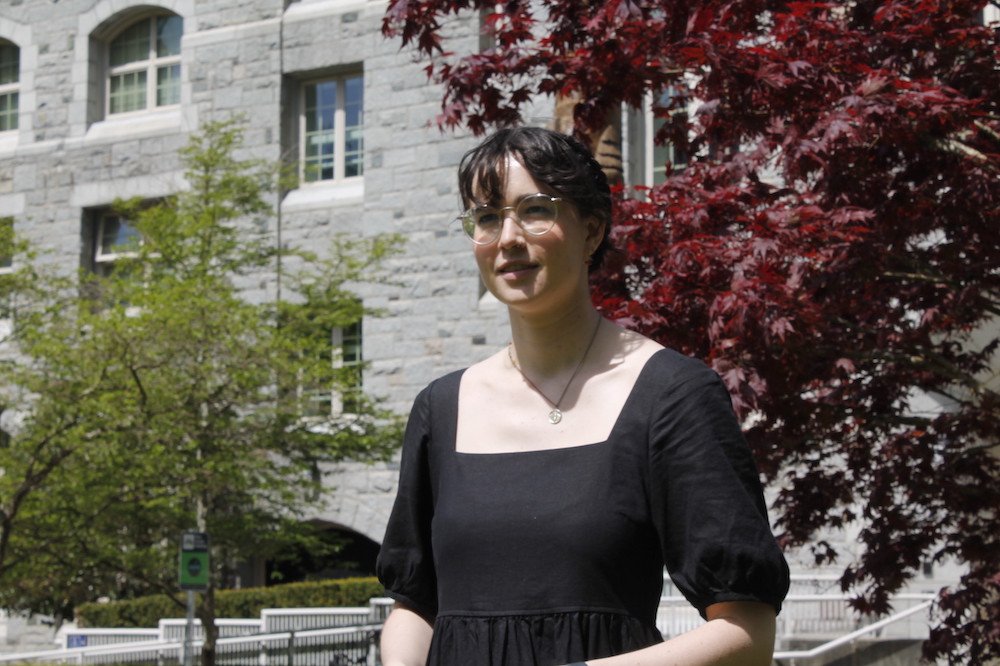 Gracy Buckholtz smiles at the camera outside a stone building at UBC.