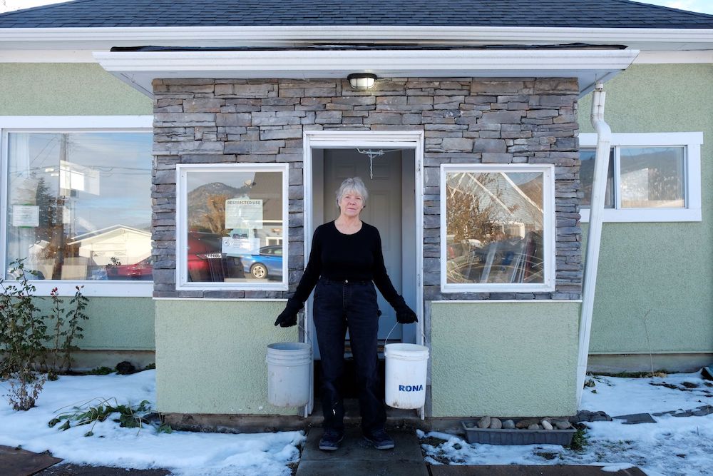Donna Rae holds two white buckets from Rona outside the front of her house.