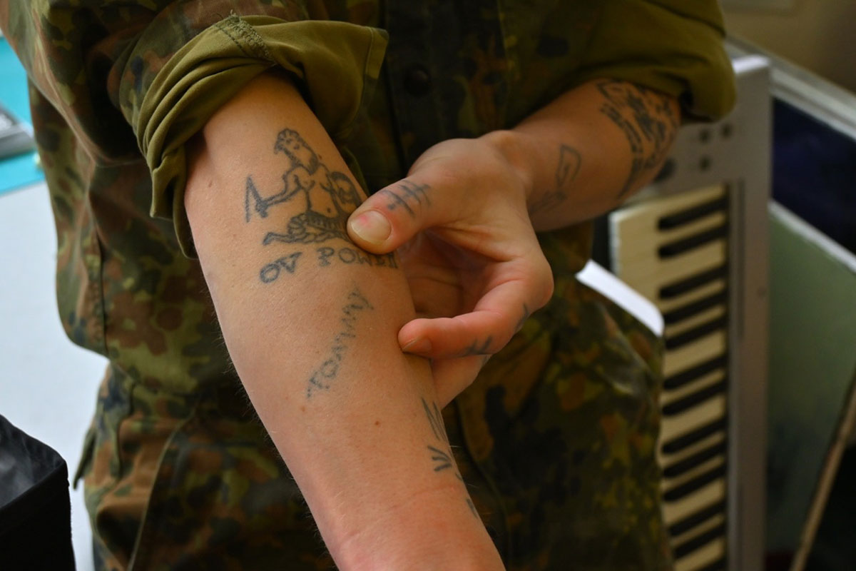 A woman holds her arm out, showing stick and poke tattoos.