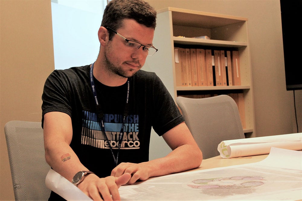 Kelly Hutchinson, in a black T-shirt, looks at plans for a memorial for the workers.