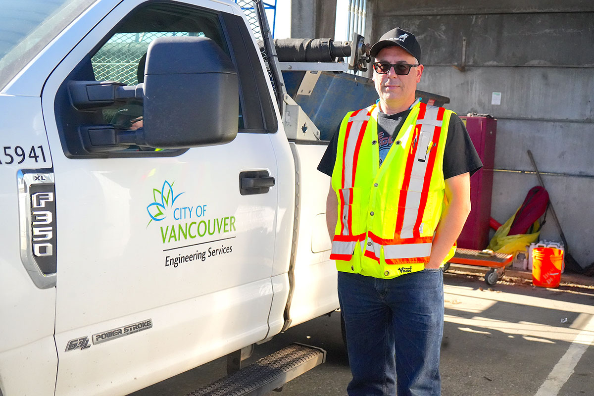 A man stands in front of a white pickup truck.