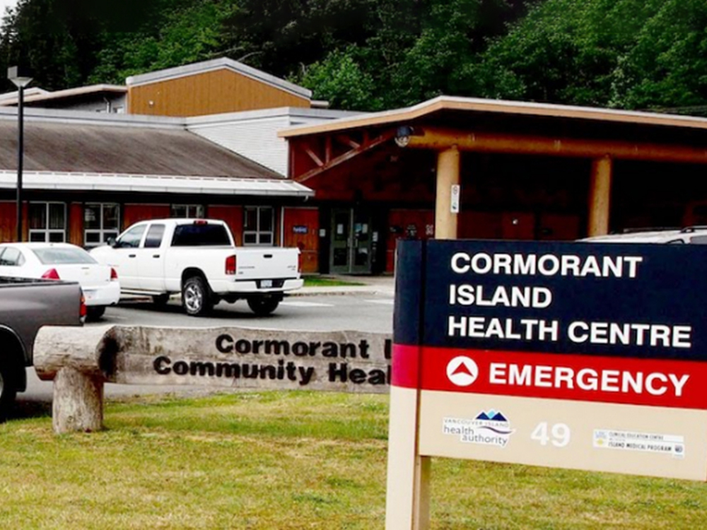 Trucks are parked outside Cormorant Island Health Centre. A sign reads “EMERGENCY.”