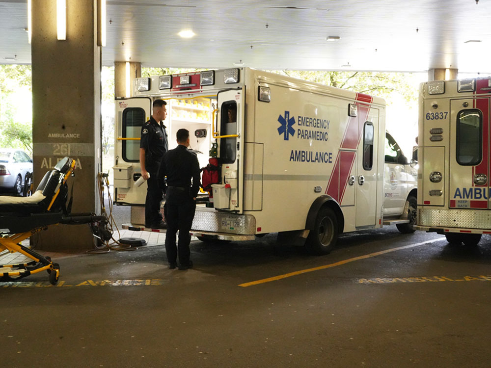 Two paramedics restock an ambulance that is located in a hospital ambulance bay.