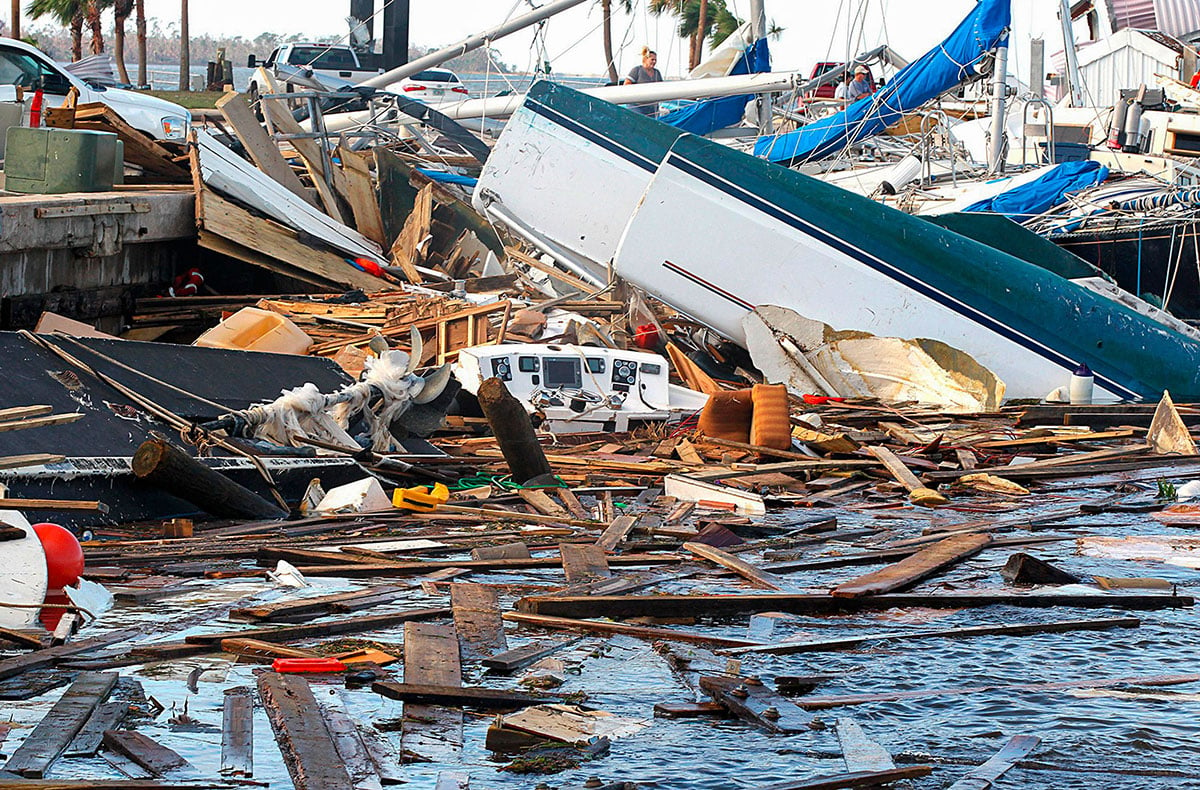 A lot of jumbled up boat parts and garbage in a marina that was recently hit by a hurricane.