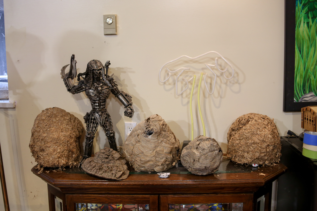 Four large round hornet and wasp nests on a cabinet with a figurine of the alien Predator.