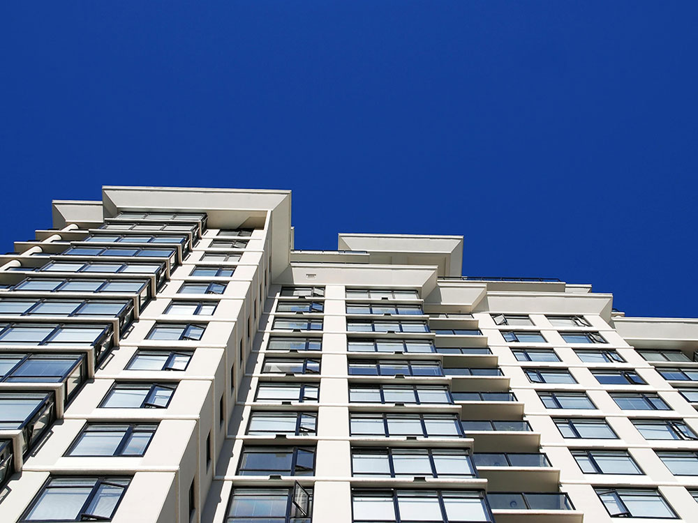 A Vancouver apartment building rises into a deep blue sky.