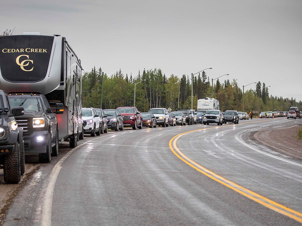 A long line of vehicles stretches down a highway under grey skies.