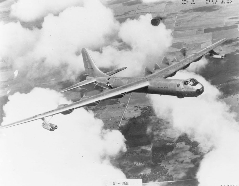 A black and white photo shows a large airplane ascending through clouds.