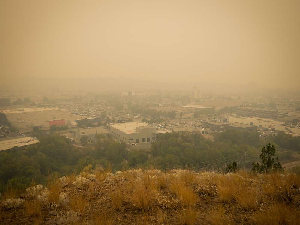 A smoky orange haze envelopes a city in the Okanagan, rendering it barely visible.
