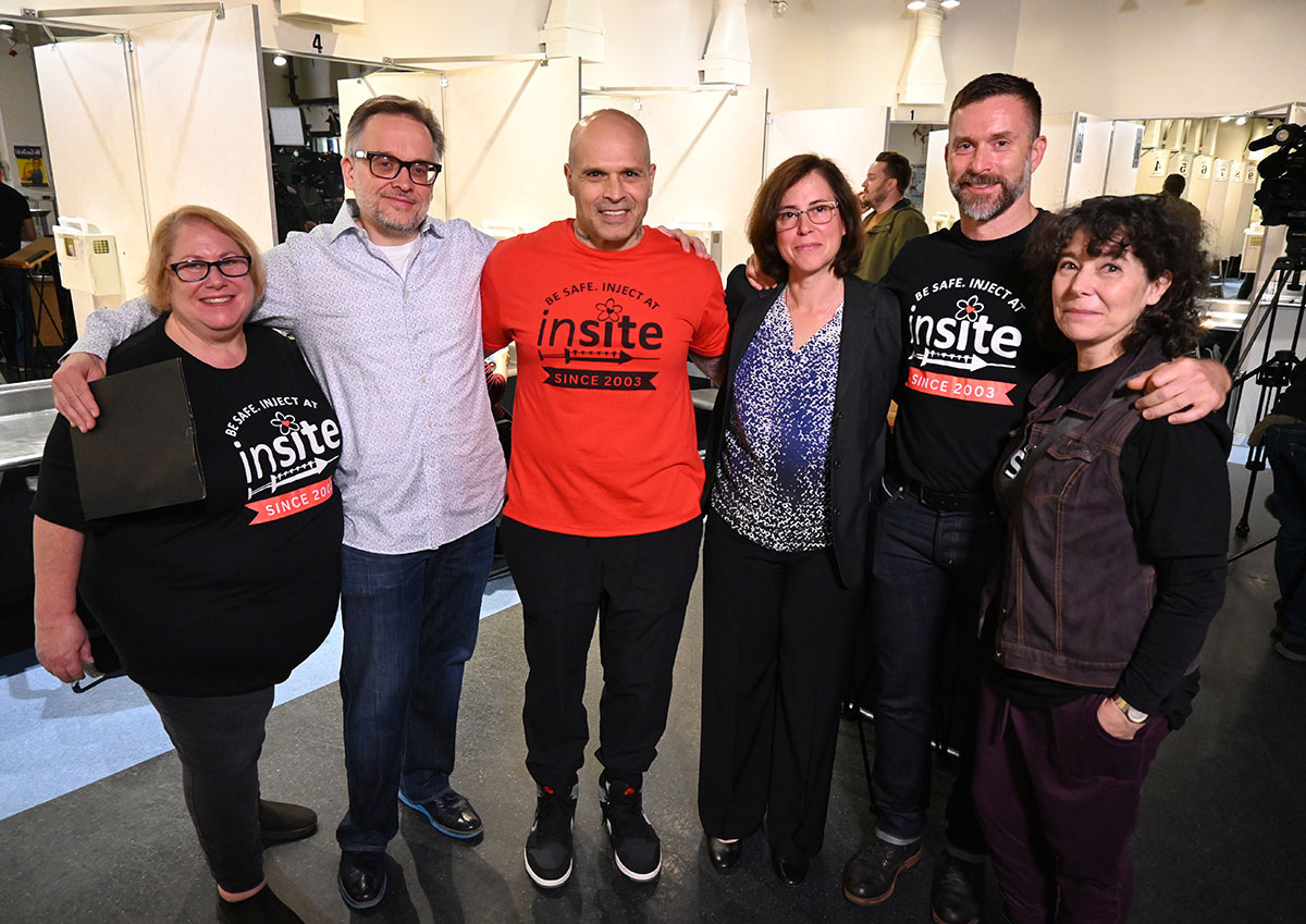 A group photo with six people. Some are wearing shirts that read ‘Be Safe. Inject at Insite.’