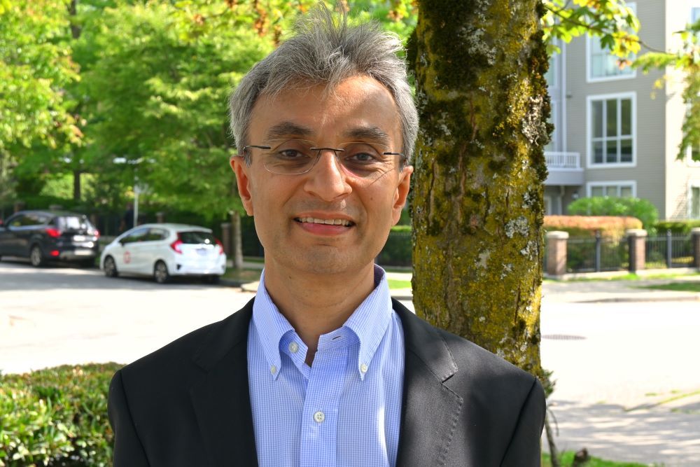 A man wearing a suit smiles at the camera.