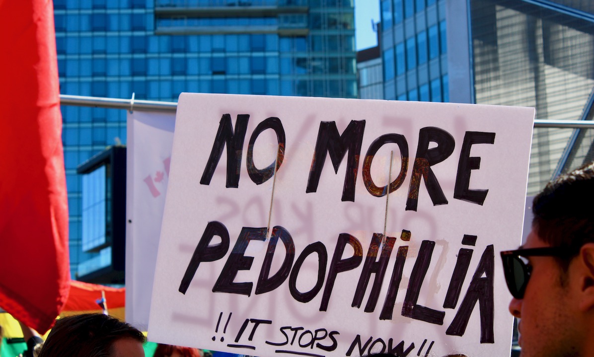 A sign at a protest reads “no more pedophilia, it stops now.”