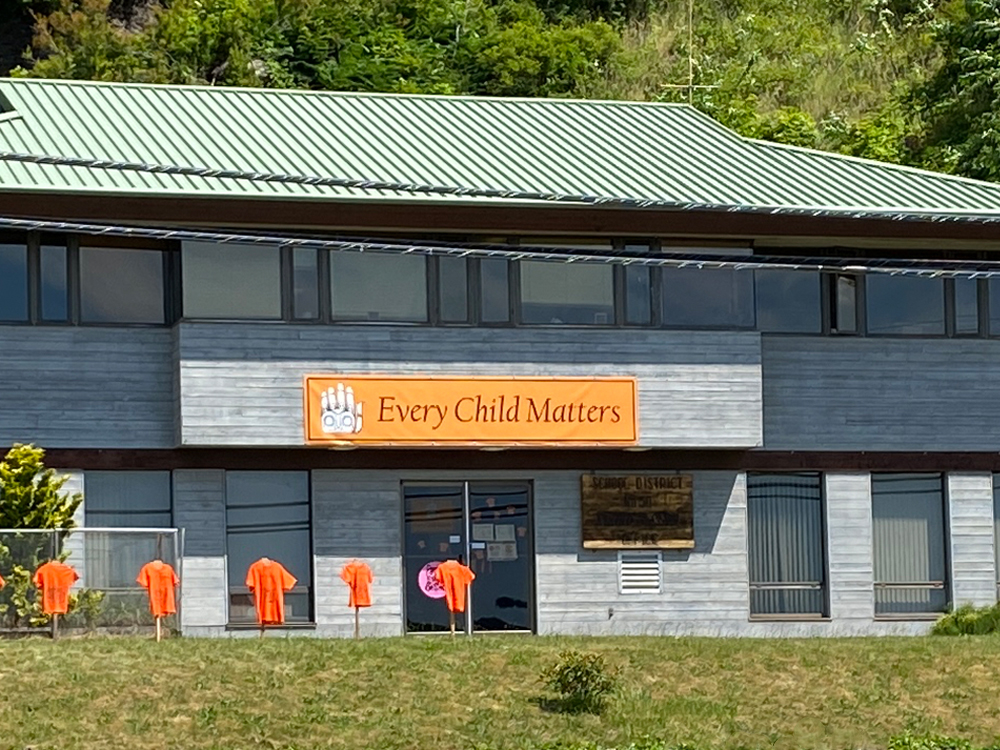 The SD50 office building in Haida Gwaii. There is an ‘Every Child Matters’ banner on the building, and orange shirts set up in front of the building.
