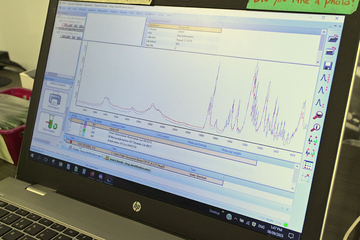 A computer screen shows a red and a blue line drawing peaks and valleys. The two lines are very similar, suggesting a match between the sample and the library’s record of heroin.