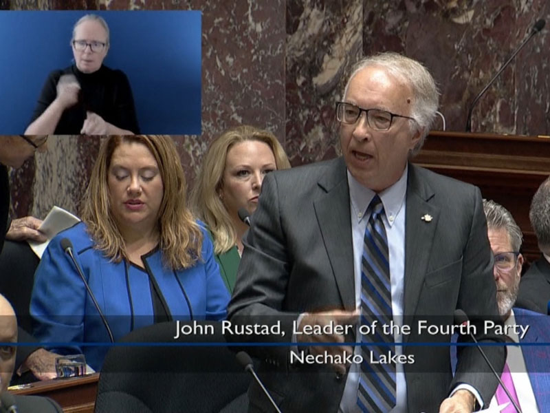 John Rustad, in a grey suit, speaks in the legislature.