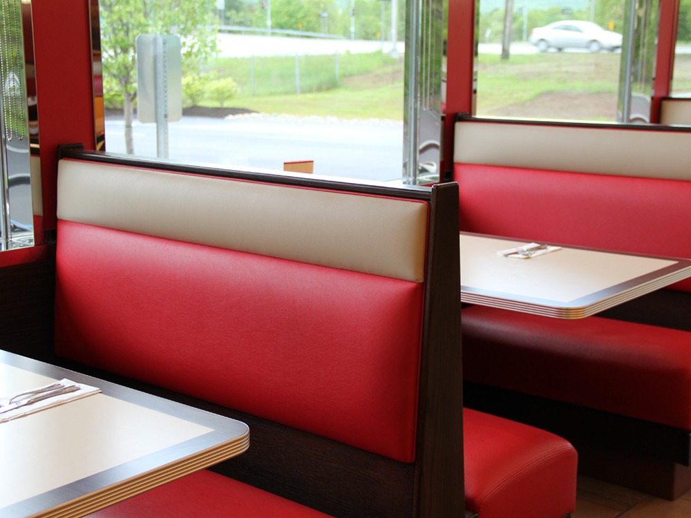 Red and tan leather booths set for breakfast at local diner, with morning sunlight streaming through windows.