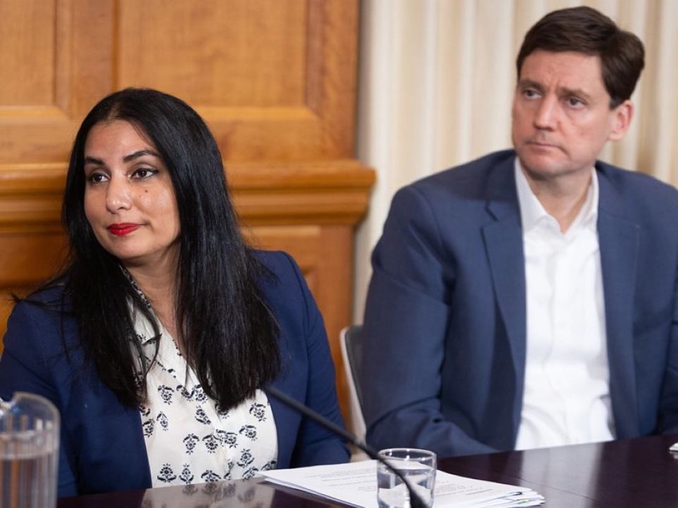 Niki Sharma, a woman with a medium skin tone and long dark hair, sits to the left of David Eby, a man with a light skin tone and short dark hair.