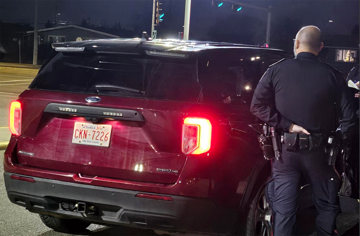 A night shot of a red SUV with a black roof and a police officer. It has no markings indicating it is a police car.