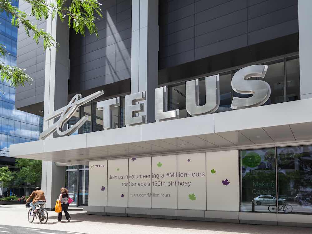 A silver Telus logo stands on the second floor of an office building.
