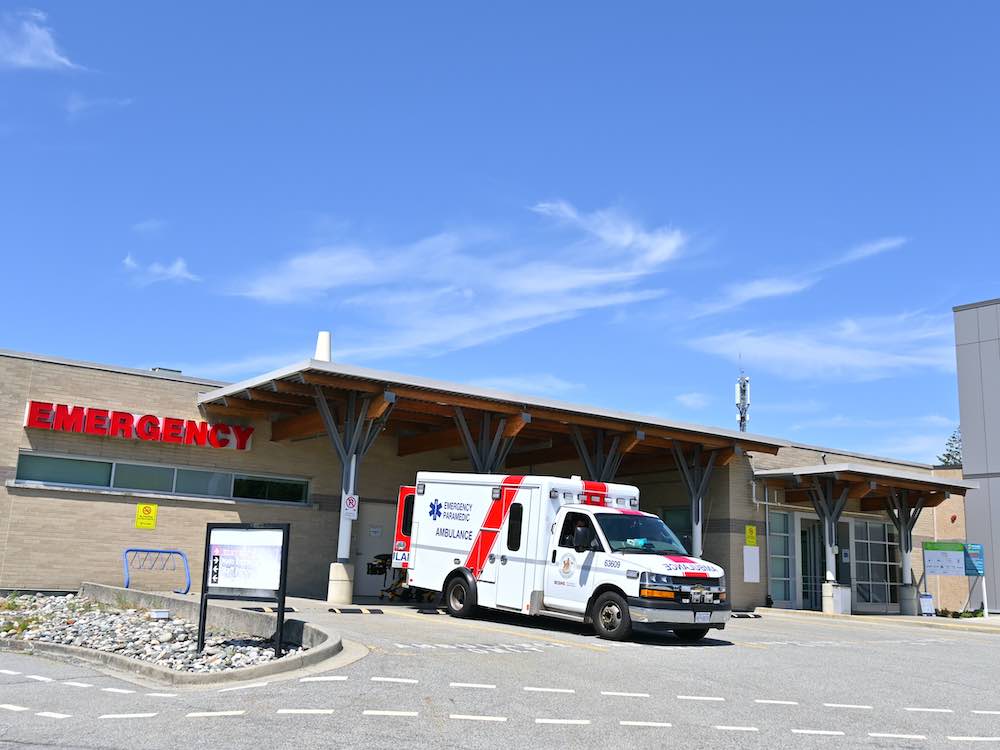An ambulance is parked outside of the Delta Hospital ER on a sunny day.