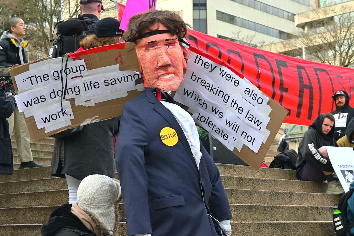 An effigy of David Eby. The quote reads: 'The group was doing life saving work, they were also breaking the law, which we will not tolerate.'