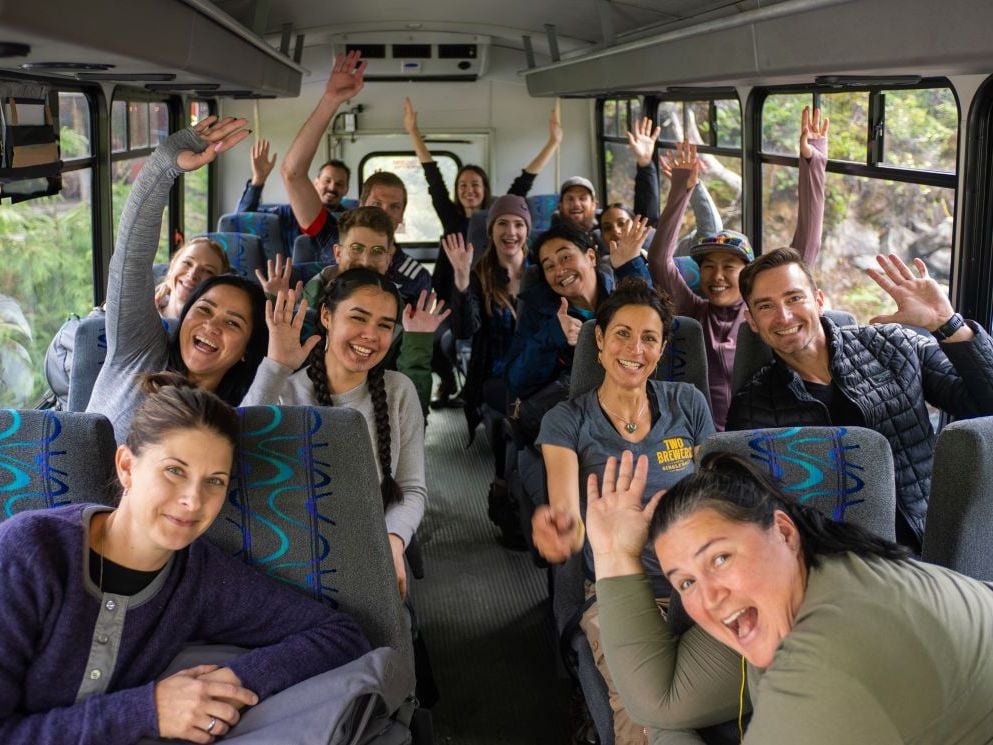 Sixteen people on a bus pose happily for the camera.
