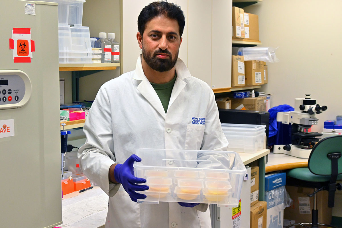 The same man poses, holding the embryos so that they are visible.