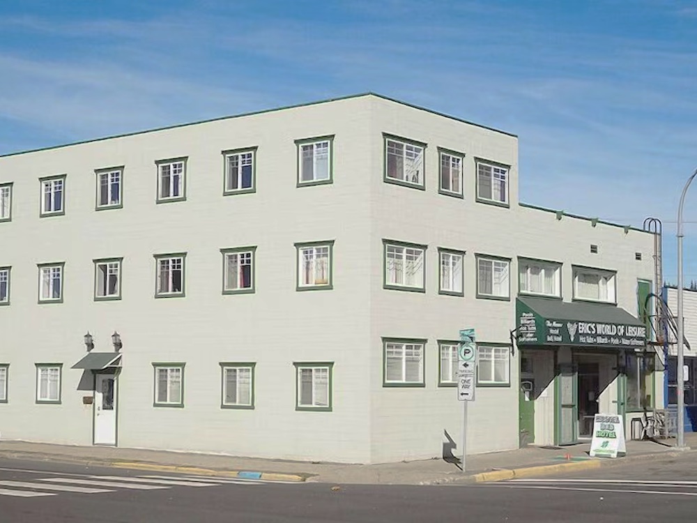 A plain white three-storey building on a city street.