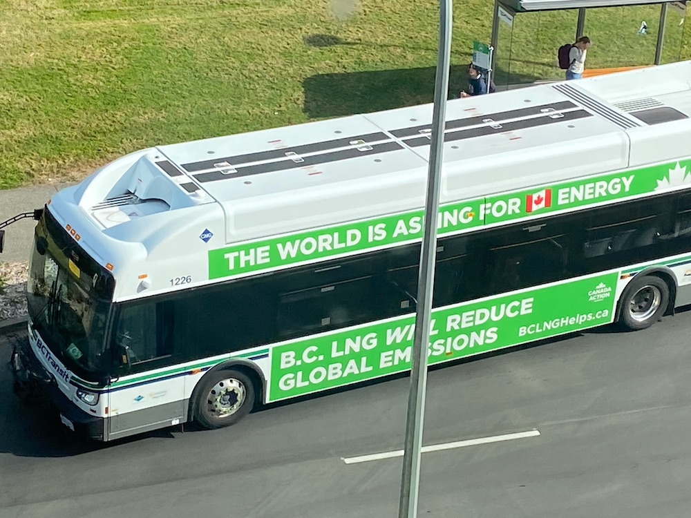 Twin bus ads read, 'THE WORLD IS ASKING FOR CANADIAN ENERGY' and 'BC LNG WILL REDUCE GLOBAL EMISSIONS,' both on a background that is a nice friendly eco-green colour.