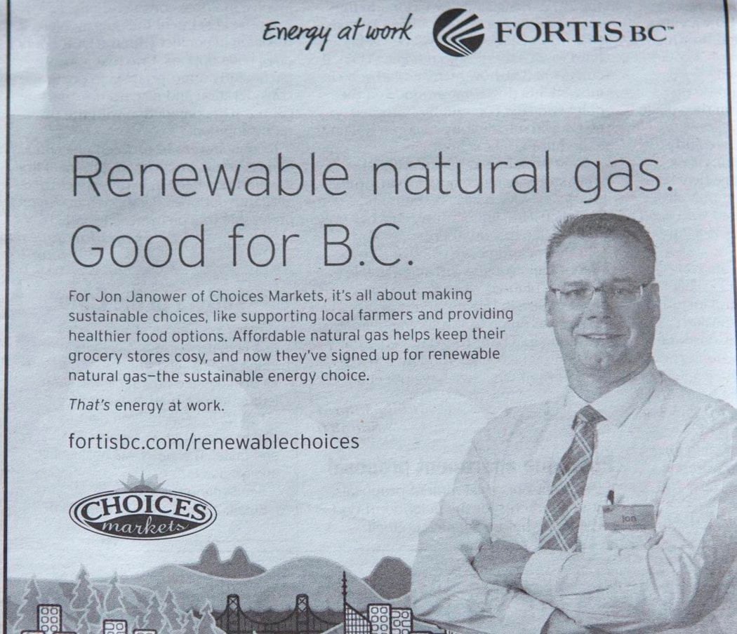 In a black and white newspaper ad, a man with short hair and glasses and wearing a tie crosses his arms and looks at the camera. The ad says, 'Renewable natural gas. Good for B.C.'