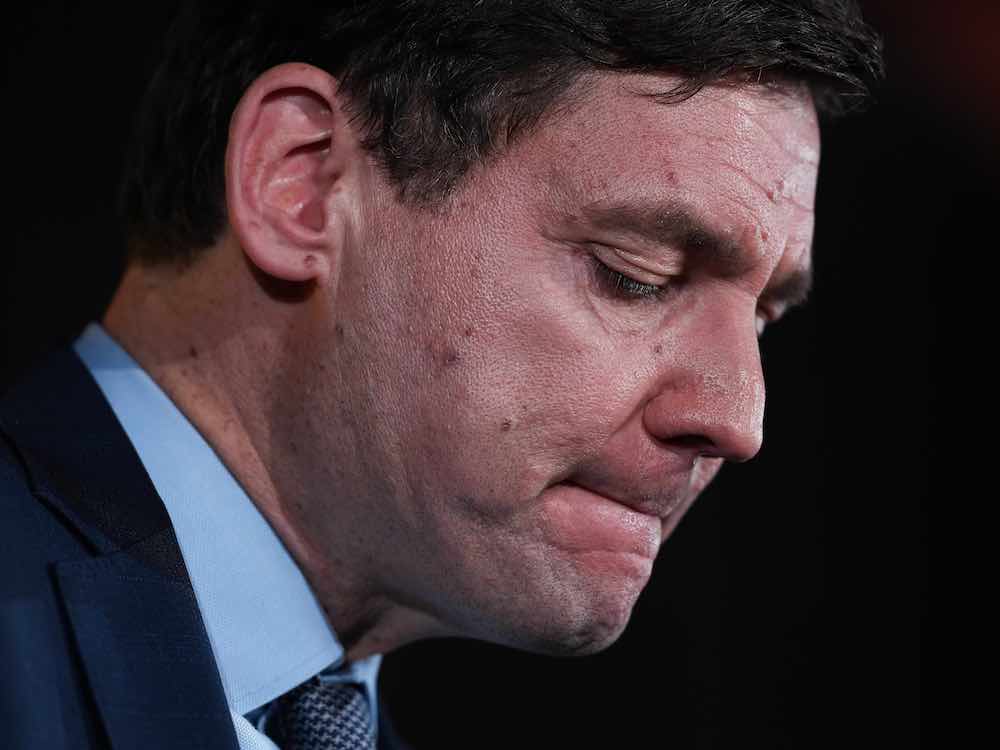 A 48-year-old, light-skinned man leans forward, with eyes closed and lips tightly drawn.