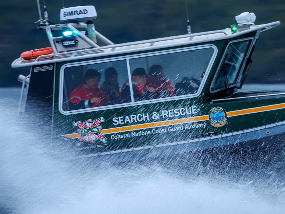 A vessel marked 'Search and Rescue' splashes water as it zips by with four rescuers inside.