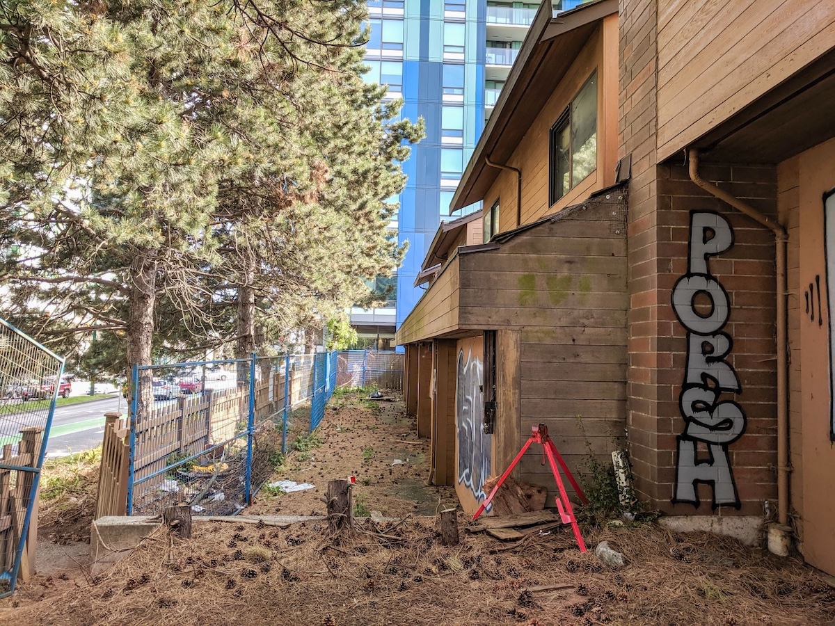 Brick and wood townhouses. To the left, a blue fence. The building is tagged 'PORSH.'