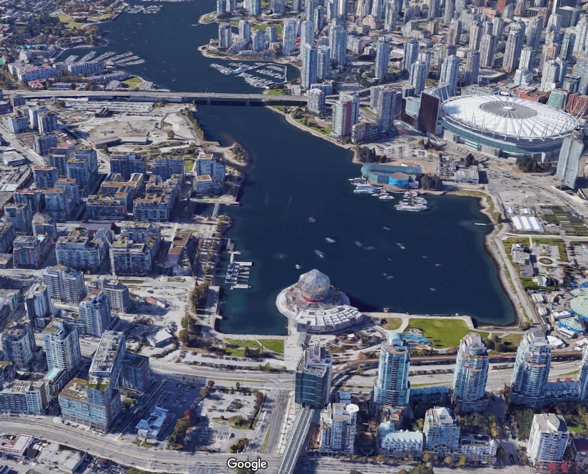 An aerial view of present-day False Creek, with the new retractable roof of BC Place to the right and Science World in the foreground, surrounded by mid- to highrise buildings.