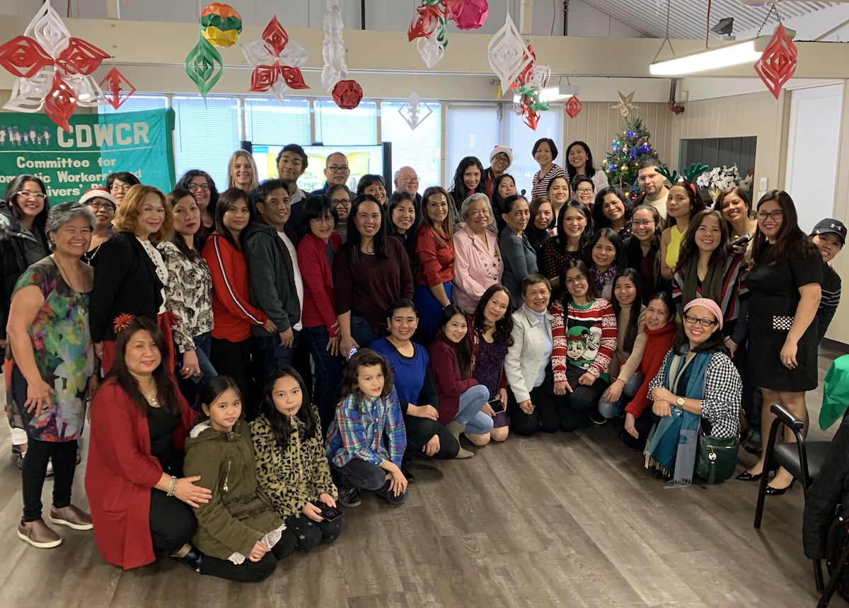 A large group of  workers and their family members pose for a photo for the Vancouver Committee for Domestic Workers&rsquo; and Caregivers&rsquo; Rights.