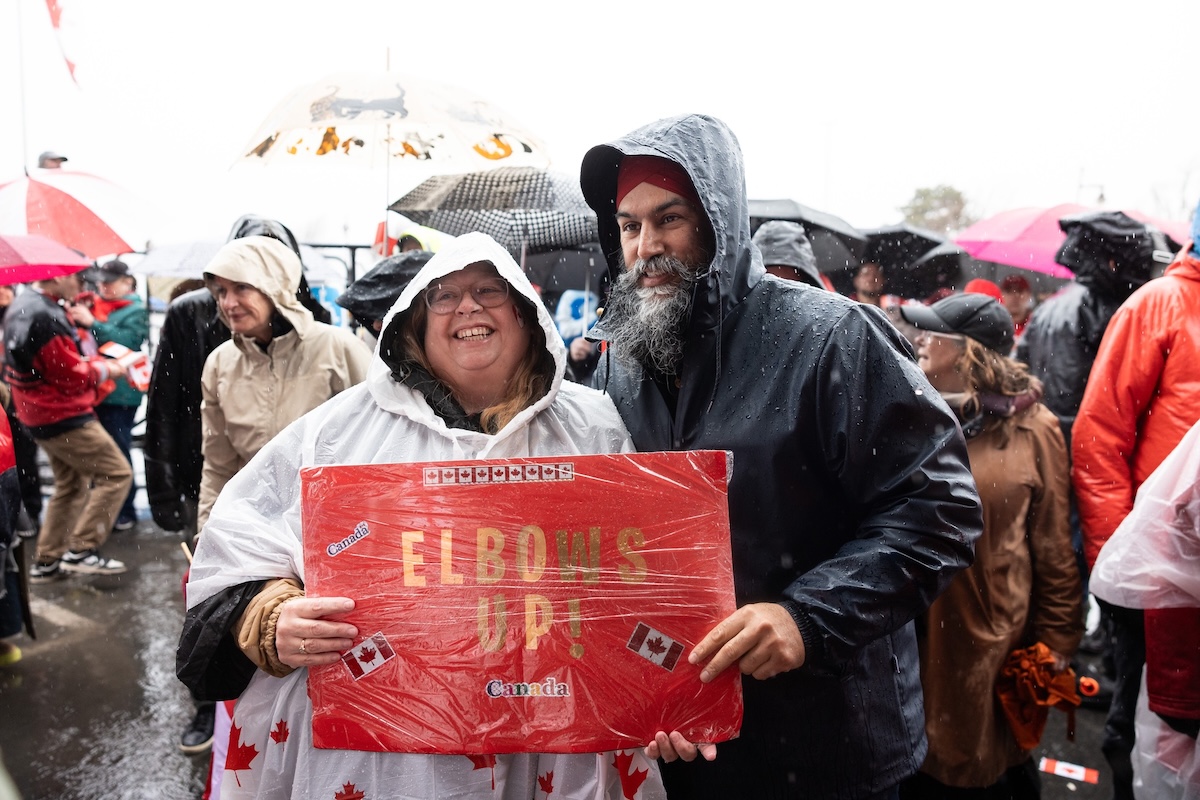 Jagmeet Singh poses with a woman holding an ‘Elbows Up’ sign.