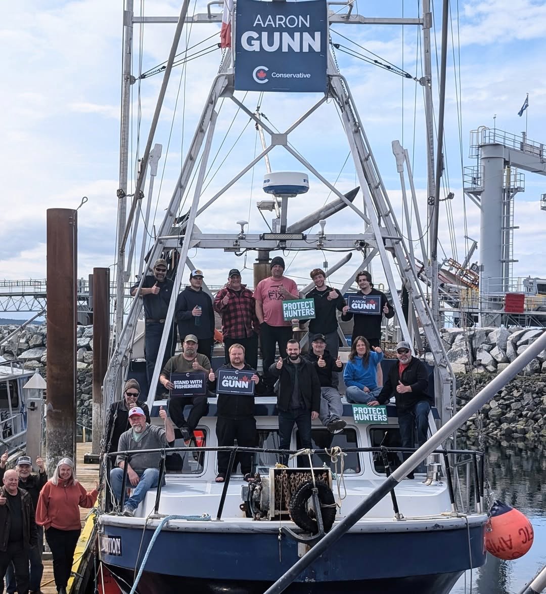 Aaron Gunn poses on a large fishing boat with supporters.