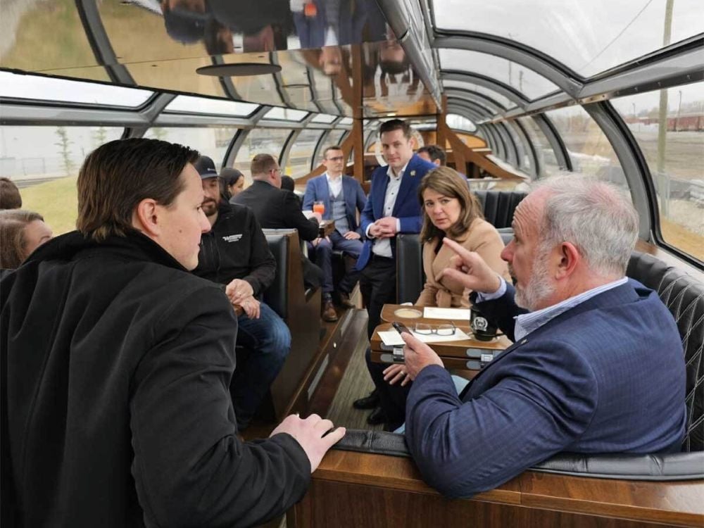 A group of people are talking in a glass-domed rail car.