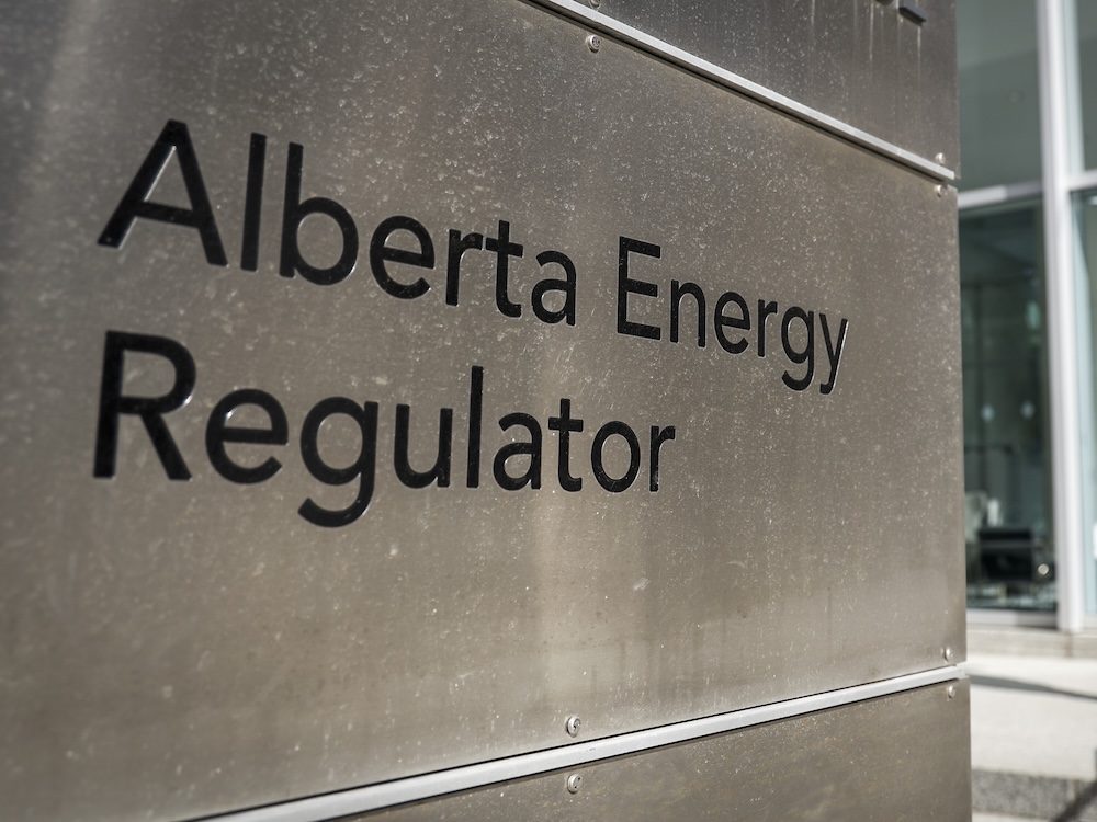 A sign says ‘Alberta Energy Regulator,’ etched black into silver metal.