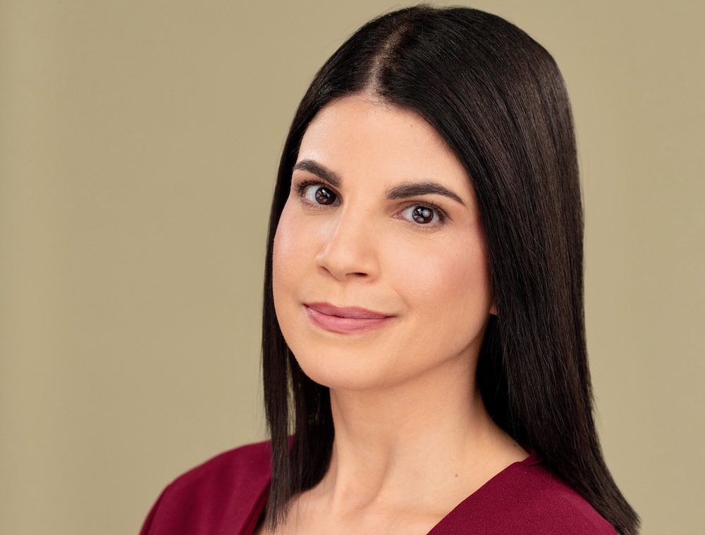 A young light-skinned woman with brown hair looks at the camera.
