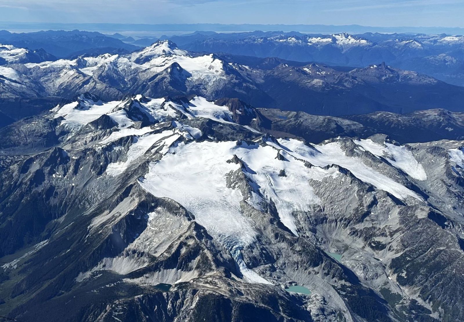 An aerial photo shows mountains and glaciers stretching toward the ocean.