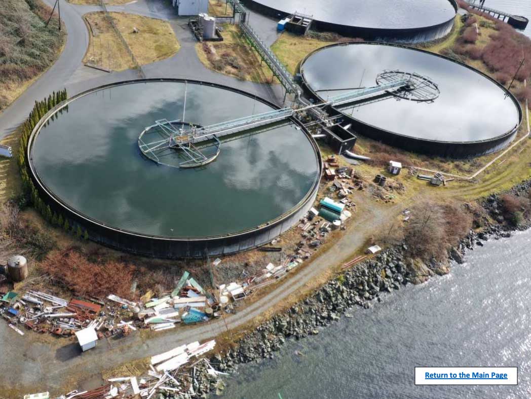An aerial photo shows two very large, very full tanks located very close to the water’s edge.