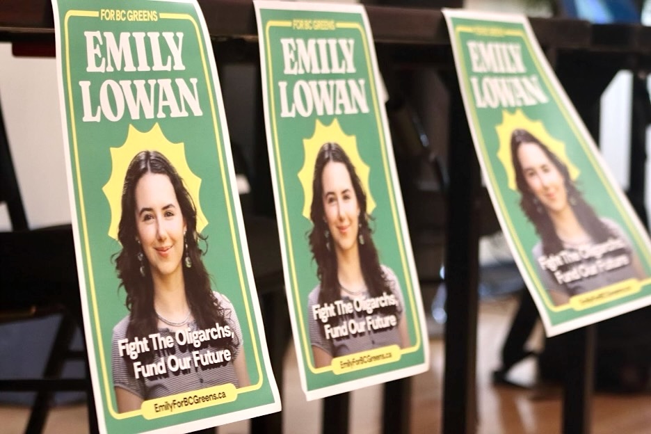 A series of paper signs featuring a young woman’s photo on a green background with the slogan ‘Fight the Oligarchs, Fund Our Future.’