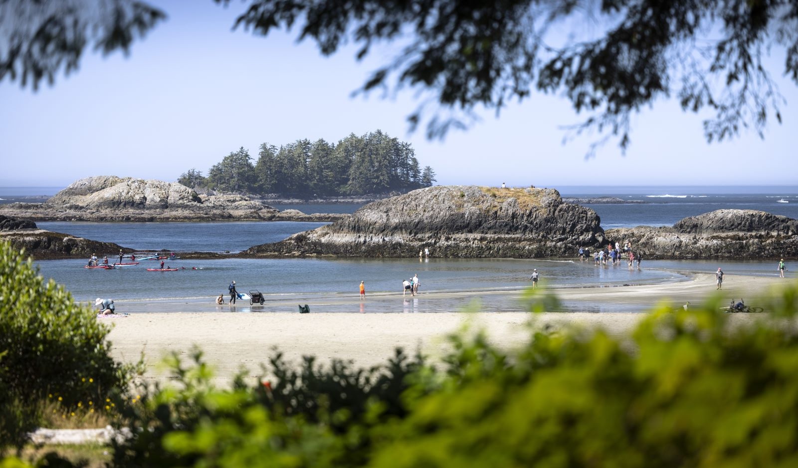 People enjoy a sheltered west coast beach with islets just off the shore.