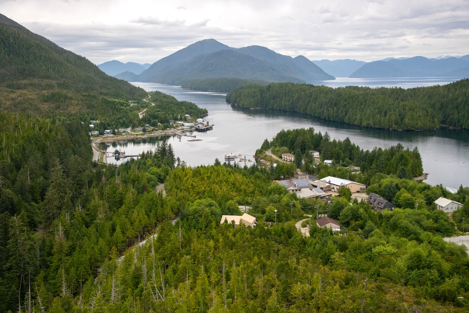 An aerial photo shows a village nestled between mountains and the sea.