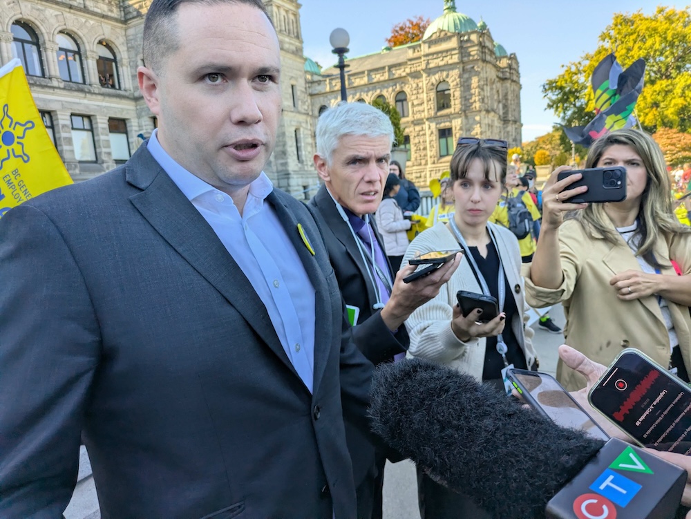 A burly middle-aged light-skinned man wearing a blue suit speaks to a group of reporters.