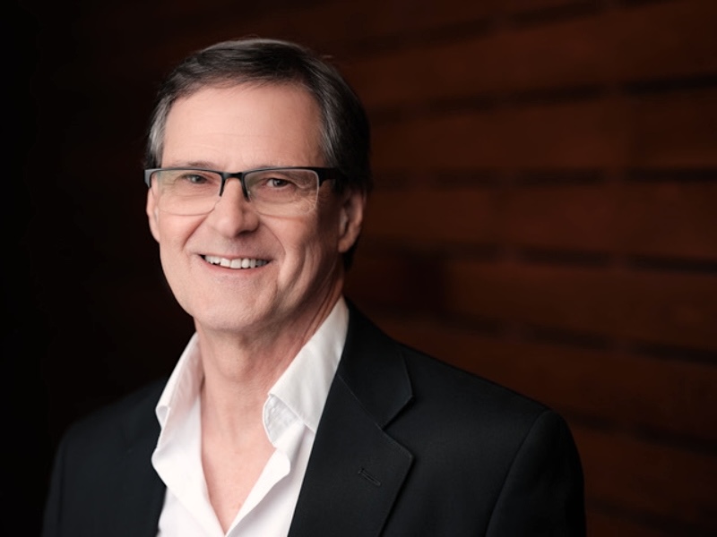 Pat Byrne is fair-skinned and wears glasses and is posing for a professionally taken headshot. He has tidy brown-grey hair.