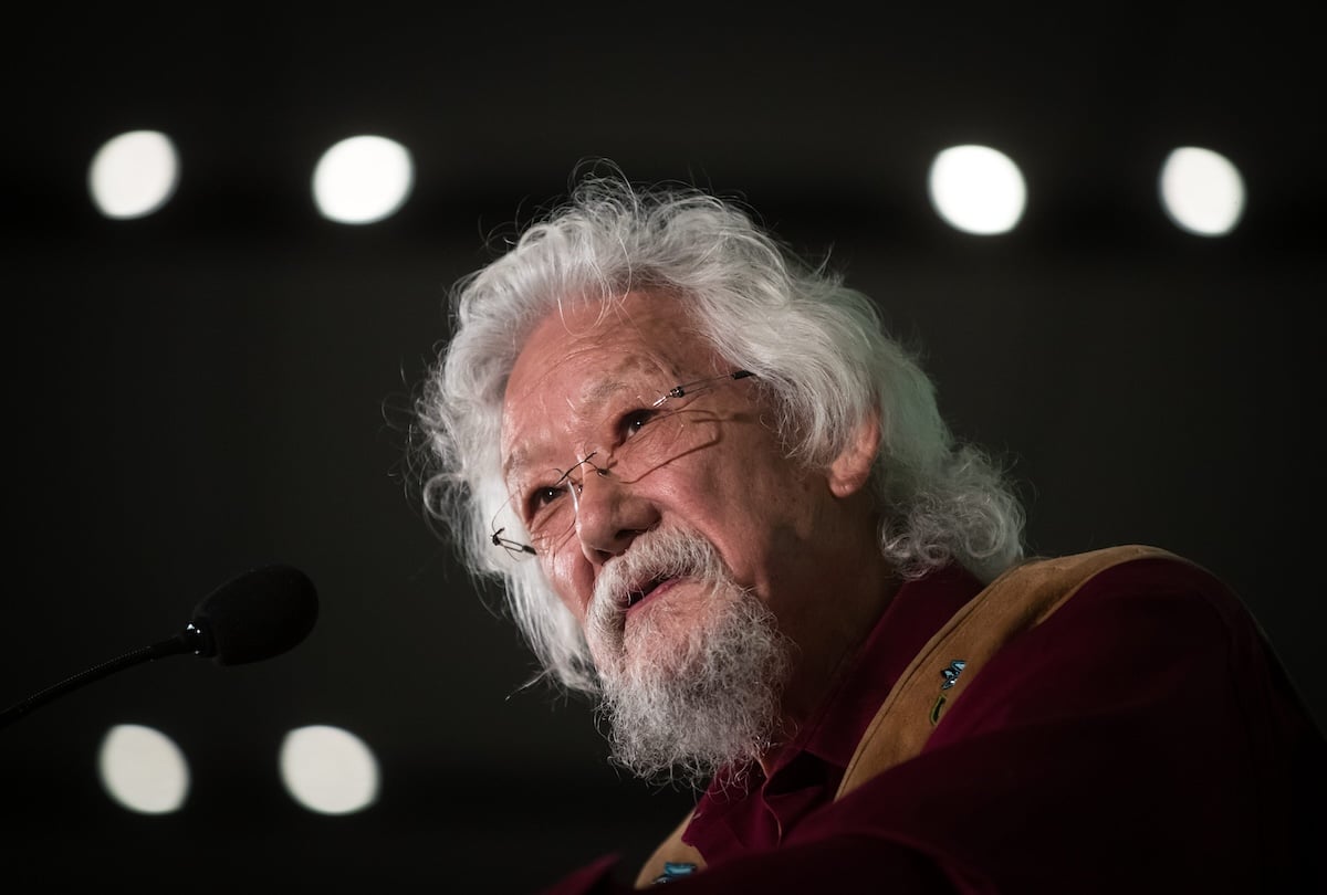 David Suzuki, with wavy white hair and a beard, speaks at a lectern.