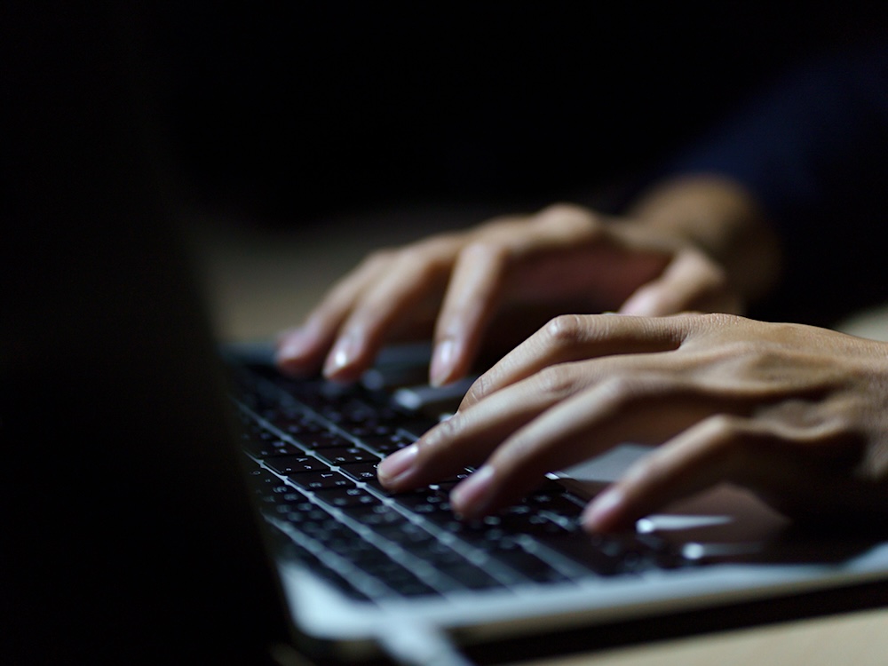 A man&rsquo;s hands type on a laptop keyboard.